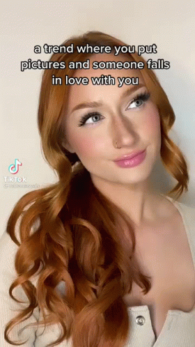 A Woman With Red Hair And Blue Eyes Is Wearing A White Shirt And A White Top . GIF