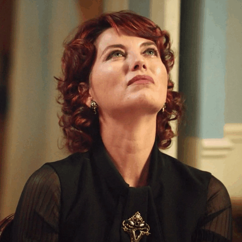 A Woman With Red Hair And Green Eyes Looks Up GIF