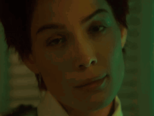 A Woman With Red Hair And Red Lipstick Is Looking At The Camera . GIF