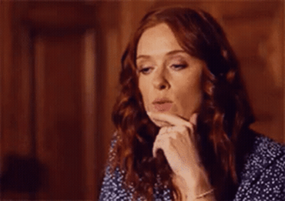 A Woman With Red Hair Is Blowing A Kiss While Holding Her Hand To Her Face . GIF