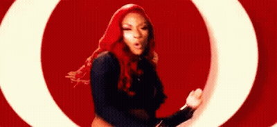 A Woman With Red Hair Is Dancing In Front Of A Red Background . GIF