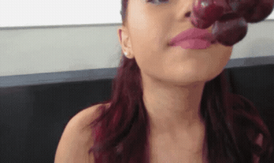 A Woman With Red Hair Is Eating Grapes With Her Mouth GIF