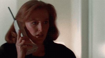 A Woman With Red Hair Is Holding A Cell Phone In Her Hand GIF