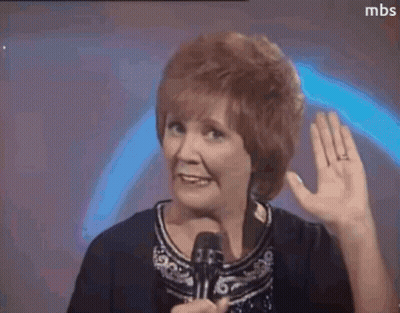 A Woman With Red Hair Is Holding A Microphone And Waving Her Hand . GIF