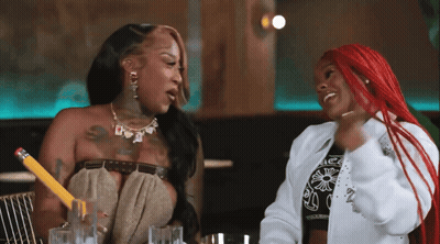 A Woman With Red Hair Is Holding A Pencil While Talking To Another Woman GIF