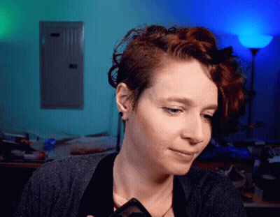 A Woman With Red Hair Is Holding A Phone In Her Hand GIF