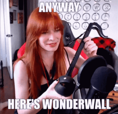 A Woman With Red Hair Is Holding A Virtual Reality Headset In Front Of A Microphone . GIF