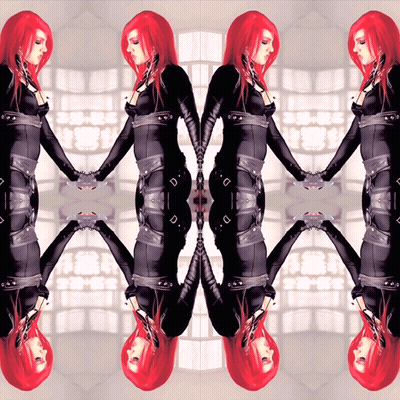 A Woman With Red Hair Is Holding Hands With Her Reflection In A Mirror GIF