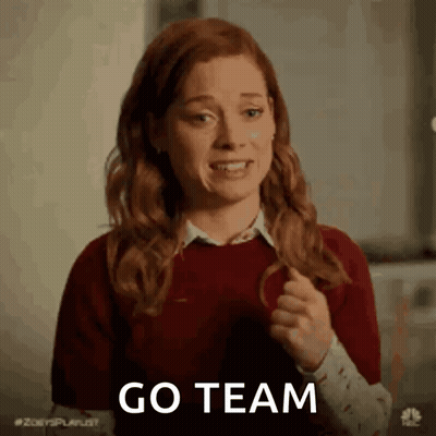 A Woman With Red Hair Is Holding Her Hair In A Ponytail And Saying Go Team . GIF
