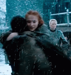 A Woman With Red Hair Is Hugging A Man With Black Hair GIF