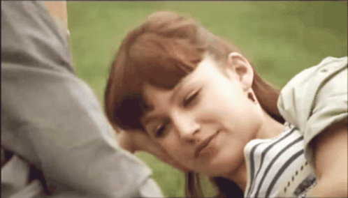 A Woman With Red Hair Is Laying On A Man 'S Lap . GIF