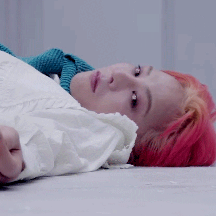 A Woman With Red Hair Is Laying On The Floor With A White Shirt On . GIF