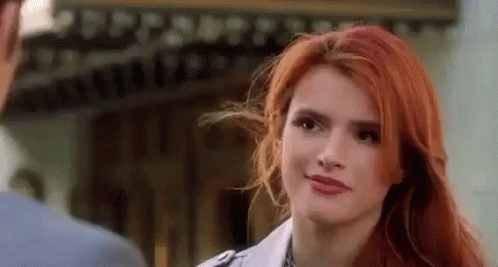 A Woman With Red Hair Is Looking At A Man In A Suit . GIF