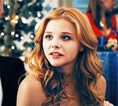 A Woman With Red Hair Is Looking At The Camera GIF
