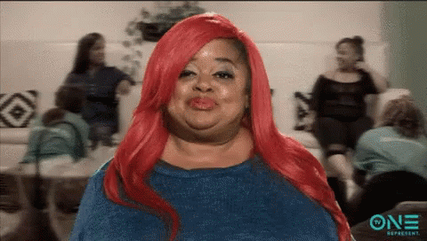 A Woman With Red Hair Is Making A Funny Face In Front Of A Group Of Women . GIF