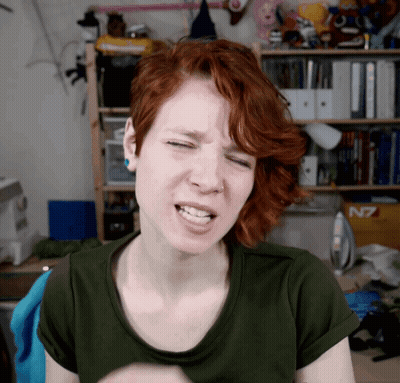 A Woman With Red Hair Is Making A Funny Face In Front Of A Shelf That Says N7 GIF