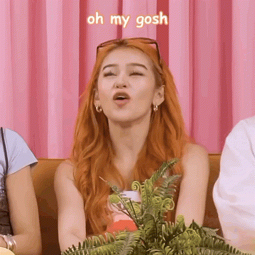 A Woman With Red Hair Is Making A Funny Face While Sitting On A Couch With Other People . GIF