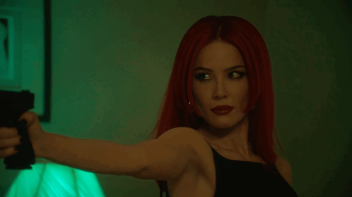 A Woman With Red Hair Is Pointing A Gun At Someone GIF