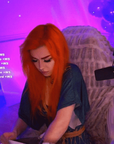 A Woman With Red Hair Is Sitting In A Chair With Purple Lights Behind Her . GIF