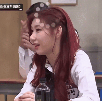 A Woman With Red Hair Is Sitting In A Classroom With A Bottle Of Water . GIF