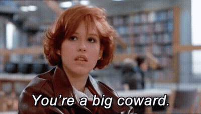A Woman With Red Hair Is Sitting In A Library With The Words `` You 'Re A Big Coward '' Written On Her Face . GIF