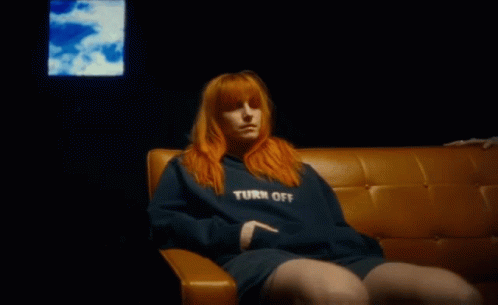A Woman With Red Hair Is Sitting On A Couch In Front Of A Television . GIF