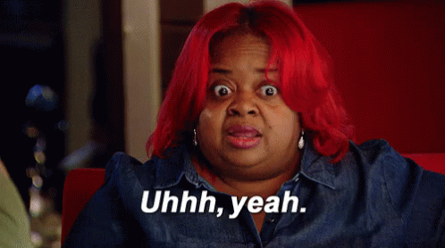 A Woman With Red Hair Is Sitting On A Red Couch And Saying Yeah . GIF