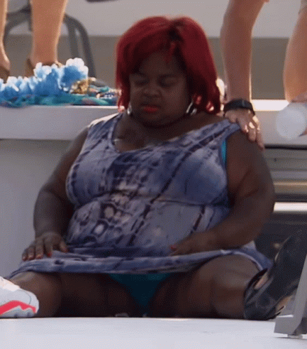 A Woman With Red Hair Is Sitting On A White Surface GIF