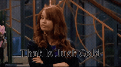 A Woman With Red Hair Is Sitting With Her Arms Crossed And The Words That Is Just Cold Behind Her GIF