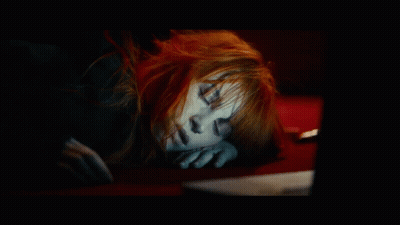 A Woman With Red Hair Is Sleeping On A Red Couch GIF