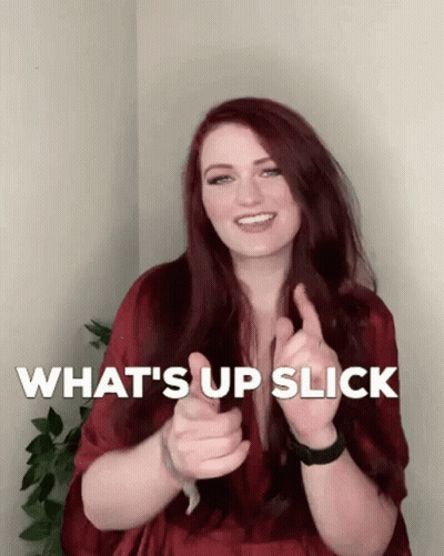 A Woman With Red Hair Is Smiling And Giving A Thumbs Up With The Words What 'S Up Slick Behind Her GIF