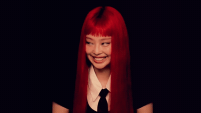 A Woman With Red Hair Is Smiling In A Black Background GIF