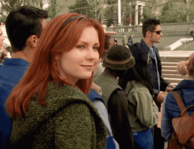 A Woman With Red Hair Is Smiling In A Crowd GIF