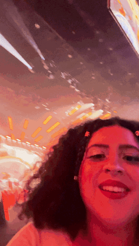 A Woman With Red Hair Is Smiling In Front Of A Blurred Background GIF