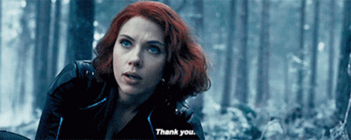 A Woman With Red Hair Is Standing In A Forest And Says Thank You . GIF