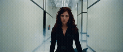 A Woman With Red Hair Is Standing In A Hallway And Looking At The Camera GIF