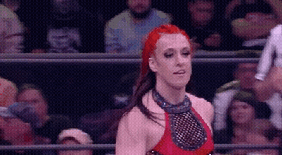 A Woman With Red Hair Is Standing In A Wrestling Ring . GIF
