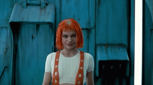 A Woman With Red Hair Is Standing In Front Of A Door GIF