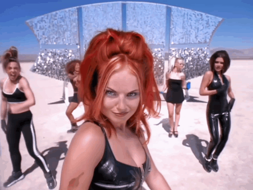 A Woman With Red Hair Is Standing In Front Of A Group Of Girls GIF