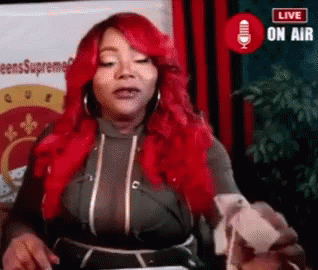 A Woman With Red Hair Is Standing In Front Of A Microphone And Talking Into It . GIF