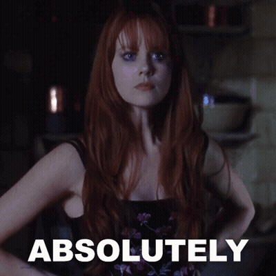 A Woman With Red Hair Is Standing In Front Of A Sign That Says " Absolutely " GIF