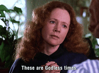 A Woman With Red Hair Is Talking To A Man And Says " These Are Godless Times " GIF