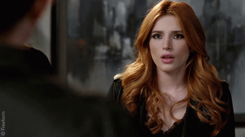 A Woman With Red Hair Is Talking To A Man In A Black Jacket GIF