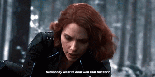 A Woman With Red Hair Is Talking To A Man In A Black Suit . GIF