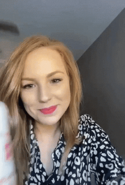 A Woman With Red Hair Is Wearing A Black And White Leopard Print Shirt And Lipstick . GIF
