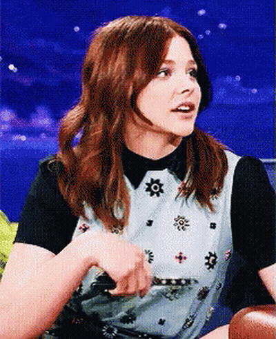 A Woman With Red Hair Is Wearing A Black And White Shirt GIF