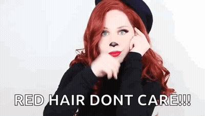 A Woman With Red Hair Is Wearing A Black Hat And Making A Face With Her Hands . GIF