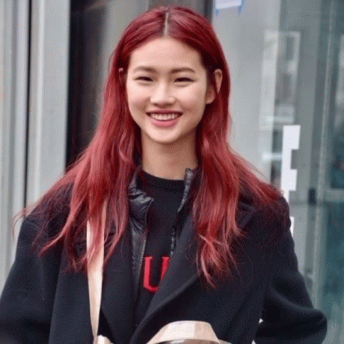 A Woman With Red Hair Is Wearing A Black Jacket And A Black Sweater With The Letter U On It GIF