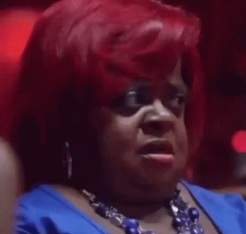 A Woman With Red Hair Is Wearing A Blue Dress And A Blue Necklace . GIF