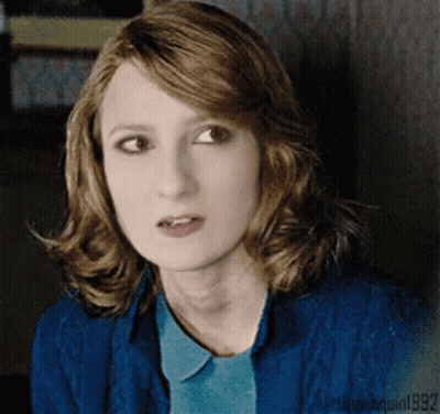 A Woman With Red Hair Is Wearing A Blue Shirt And A Blue Sweater GIF
